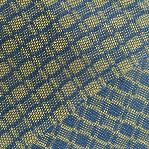 May include: Close-up of a woven textile with a repeating pattern of yellow and navy blue diamond shapes. The fabric has a textured appearance, with the pattern creating a sense of depth and visual interest. The textile is likely used for home decor or apparel.