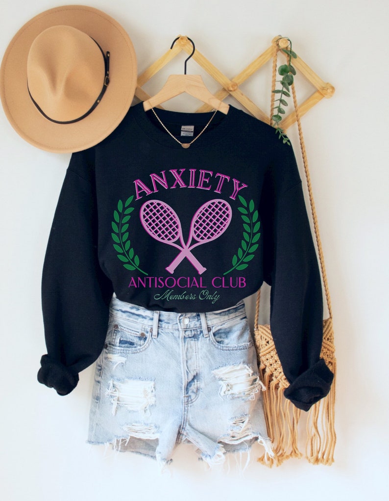 May include: Black sweatshirt with a pink and green graphic that says "Anxiety Antisocial Club Members Only" with two pink tennis rackets crossed over each other.