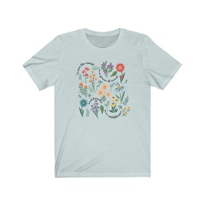 May include: Light blue t-shirt with a floral design and the text "To see the world as a grain of sand and heaven in a wildflower."