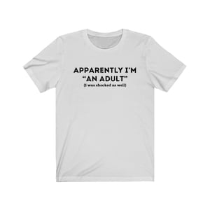 May include: White t-shirt with black text that reads "Apparently I'm "An Adult" (I was shocked as well)"