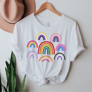 May include: White t-shirt with a design of multiple colorful rainbows.