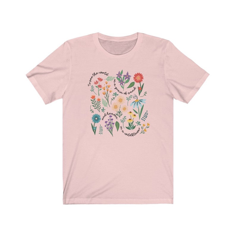 May include: Pink t-shirt with a floral design and the text "To see the world as a grain of sand and heaven in a wildflower."