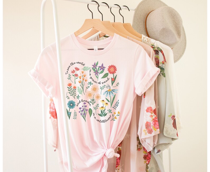 May include: Pink t-shirt with a floral design and the text "To see the world in a grain of sand and heaven in a wildflower."