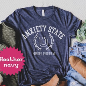 May include: Heather navy blue t-shirt with white text that reads "Anxiety State - Honors Program" with a white letter U inside a wreath.