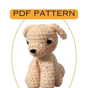 May include: A crocheted amigurumi puppy toy in a cream colour. The puppy is sitting with its head tilted to the side and has black eyes.