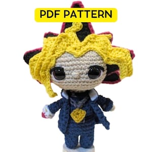 Könnte beinhalten: Gehäkelte Puppe einer Figur mit stacheligem gelbem Haar, die eine dunkelblaue Jacke und einen goldenen Anhänger trägt. Die Puppe hat große schwarze Augen und ist mit "PDF PATTERN" in einem gelben Banner beschriftet.