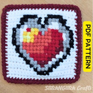 May include: A square crochet piece featuring a pixelated heart design in shades of red, orange, and yellow, outlined in black and grey on a white background, with a dark red border. The text PDF PATTERN is visible on a yellow vertical tab.