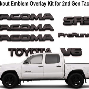 Könnte beinhalten: Ein Blackout-Emblem-Overlay-Kit für den Tacoma der 2. Generation mit mattschwarzen Kunststoffbuchstaben, bestehend aus drei TACOMA-Emblemen, einem SR5-Emblem, einem PreRunner-Emblem, einem TOYOTA-Emblem und einem V6-Emblem über einem weißen Pickup.