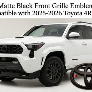 Może przedstawiać: Matowo-czarny emblemat na przedni grill obok białego SUV-a Toyota 4Runner. Tekst głosi: Matte Black Front Grille Emblem Compatible with 2025-2026 Toyota 4Runner. Emblemat przedstawia charakterystyczne logo Toyoty składające się z trzech owali.
