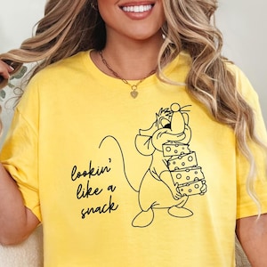 May include: Yellow t-shirt with a black line drawing of a cartoon mouse holding a stack of cheese. The text "lookin' like a snack" is printed on the shirt.