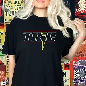 May include: Black t-shirt with a white graphic of the word "TRIC" with a yellow lightning bolt.