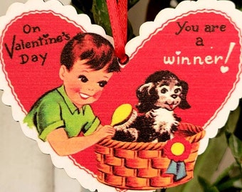 May include: A red heart-shaped Valentine's Day card with a boy giving a puppy a bath in a wicker basket. The card reads "On Valentine's Day" on the left side and "You are a winner!" on the right side.