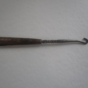 May include: A vintage metal shoe horn with a wooden handle. The handle is decorated with an intricate floral pattern.