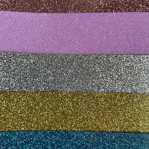 Op de afbeelding: Vijf stroken glitterpapier in verschillende kleuren: bruin, paars, zilver, goud en blauw.