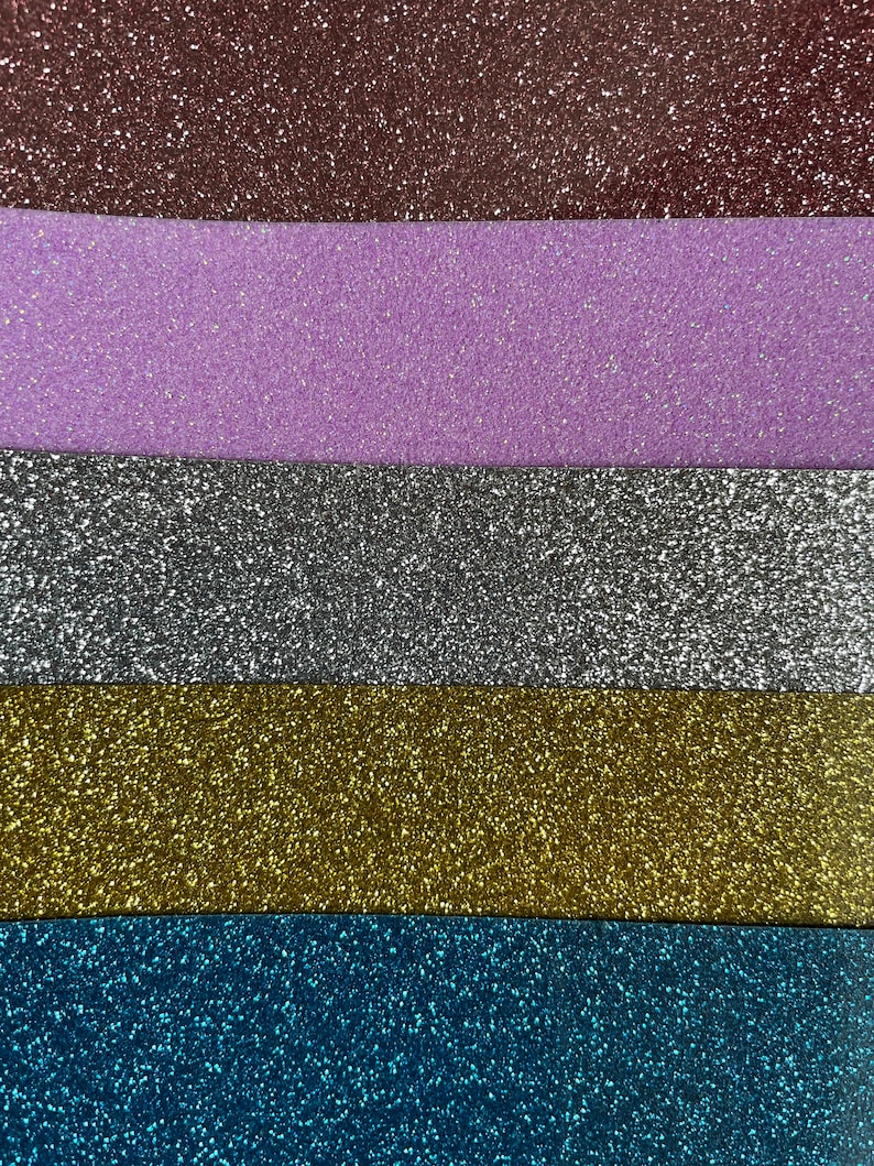 Op de afbeelding: Vijf stroken glitterpapier in verschillende kleuren: bruin, paars, zilver, goud en blauw.