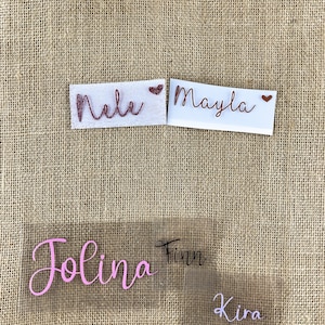 Op de afbeelding: Vier strijklabels met verschillende namen. De namen zijn "Nele", "Mayla", "Jolina" en "Kira". De labels zijn op een jute achtergrond.