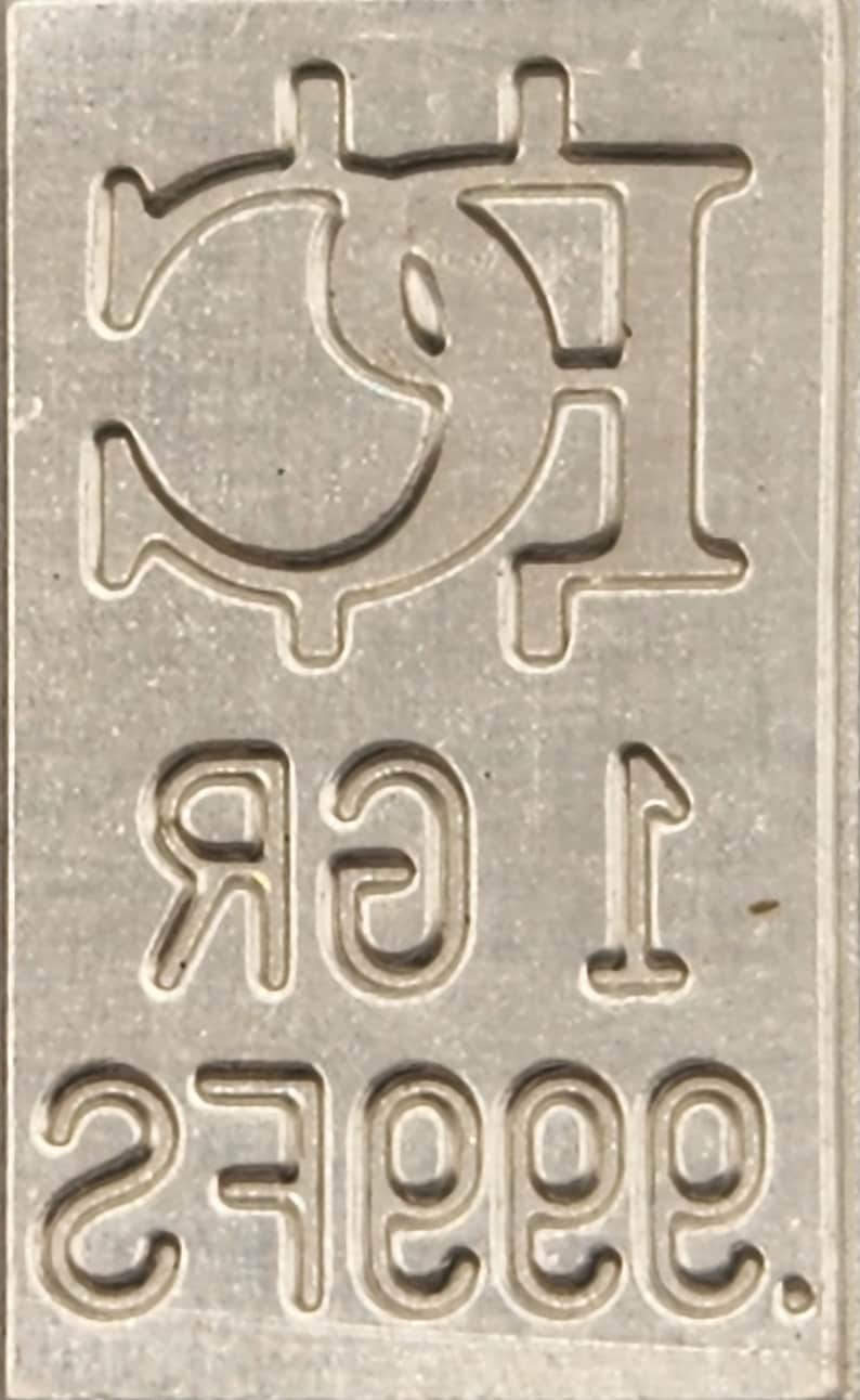 Op de afbeelding: Een zilveren staaf met een Bitcoin-symbool en de tekst "1 gr .9999 Fine" erop gegraveerd.