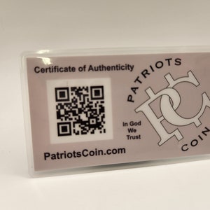 Peut inclure: Une carte blanche avec un certificat d'authenticit&eacute; pour une pi&egrave;ce de monnaie Patriots. La carte comporte un code QR noir et blanc, le texte "Patriots Coin.com" et le texte "In God We Trust".
