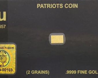 Pode incluir: Um cartão preto com letras douradas que dizem "PATRIOTS COIN" e "2GR-G-00103 (2 GRAINS)". O cartão também apresenta um pequeno quadrado dourado com o texto "2GR" e um adesivo holográfico com o texto "PATRIOTS COIN".
