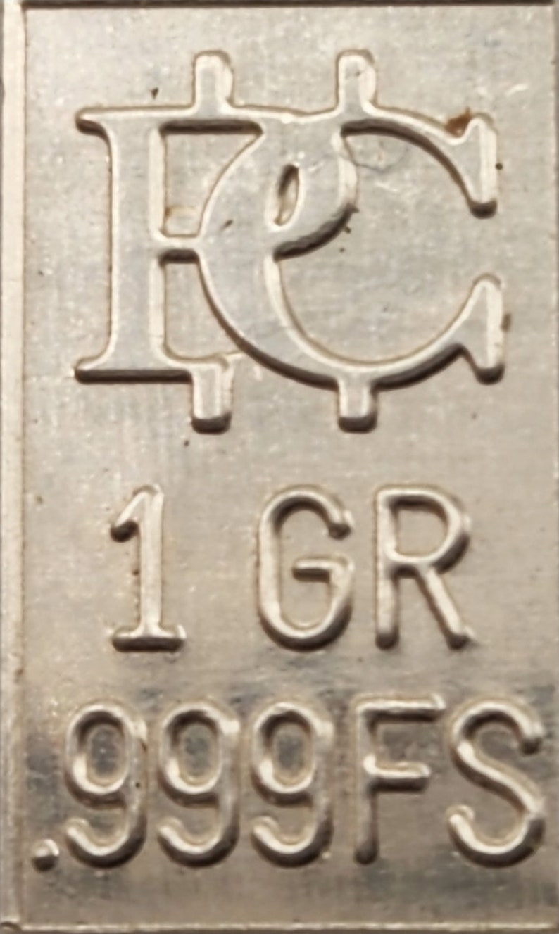 Op de afbeelding: Een zilveren staaf met de inscriptie "1 GR 999FS" en een gestileerd "FC"-logo.