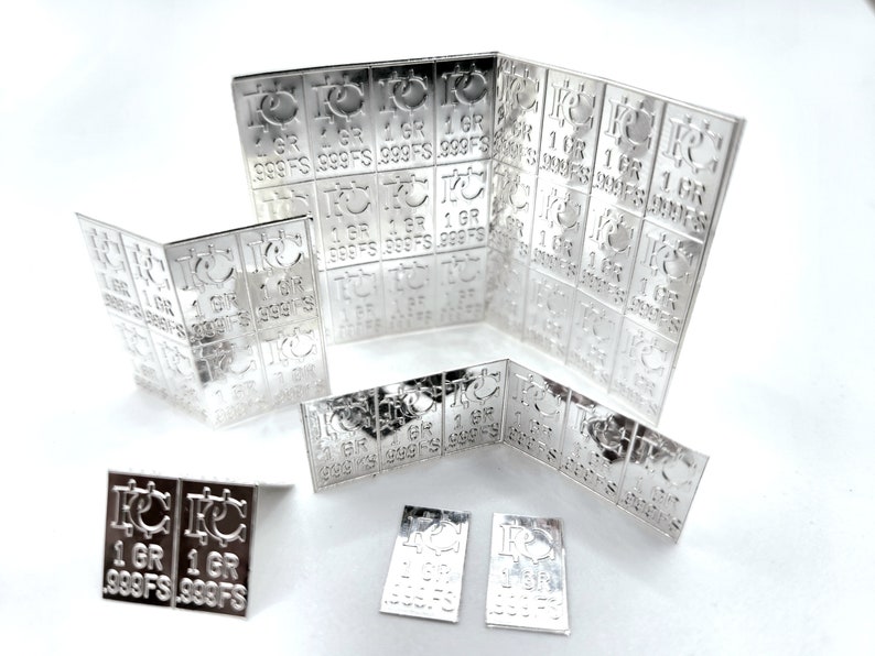 Peut inclure: Une collection de lingots d'argent, chacun estampill&eacute; "1 GR 999FS". Les lingots sont dispos&eacute;s en grille, certains &eacute;tant pli&eacute;s pour montrer l'inscription des deux c&ocirc;t&eacute;s.