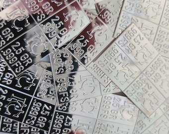 May include: A close-up of a pile of silver bars. Each bar is stamped with "2.5 GR 999FS" and a small symbol. The bars are stacked on top of each other, creating a textured surface.