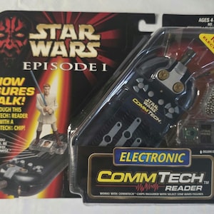 May include: A Star Wars Episode I Electronic CommTech Reader toy, packaged in a clear plastic case. The packaging features Darth Maul and a figure of Obi-Wan Kenobi. The reader is black with silver accents and the text "COMMTECH READER".