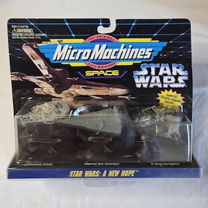 May include: A sealed Micro Machines Star Wars toy set. The packaging features the Star Wars logo and the text "A New Hope." The set includes miniature models of the Millennium Falcon, an Imperial Star Destroyer, and an X-wing Starfighter.