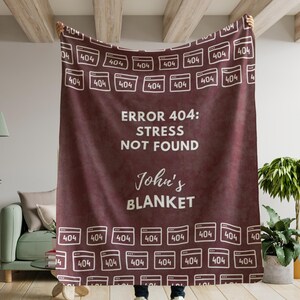 May include: A maroon fleece blanket with a white 404 error message pattern and the text "ERROR 404: STRESS NOT FOUND John's BLANKET".