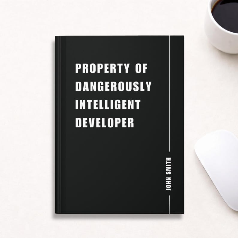 May include: Black notebook with the text "PROPERTY OF DANGEROUSLY INTELLIGENT DEVELOPER" in white. The name "JOHN SMITH" is printed vertically on the right side. A white computer mouse and a cup of coffee are in the background.