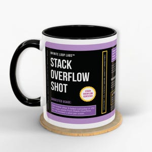 May include: A white ceramic mug with a black handle and interior. The mug features the text "STACK OVERFLOW SHOT" in large white letters on a black background, with additional text and a "STACK OVERFLOW CERTIFIED" sticker. The mug sits on a wooden coaster.
