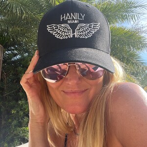 May include: A black baseball cap with white embroidered wings and the text "HANILY MIAMI".