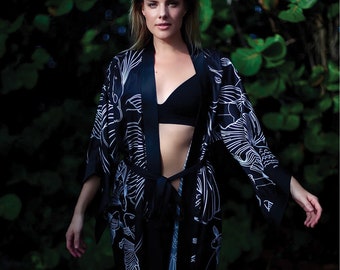 May include: A black silk robe with a white floral pattern. The robe has a sash tie and long sleeves.