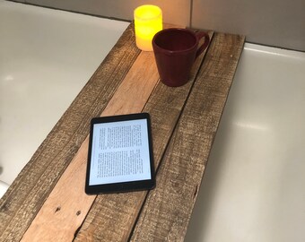 Puede incluir: Una bandeja de baño de madera con una tableta, una taza roja y una vela. La bandeja está hecha de madera reciclada y tiene un aspecto rústico.