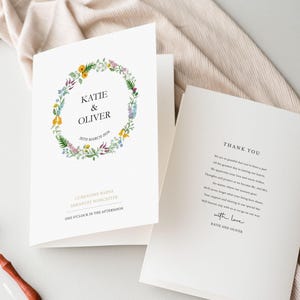 May include: A white folded wedding invitation card featuring a colourful floral wreath illustration surrounding the text Katie & Oliver 30th March 2020, with Curradine Barns Shrawley Worcester and One O'Clock in the Afternoon printed below the wreath.