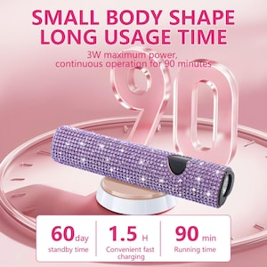 Könnte beinhalten: Ein lila Gerät mit Kristallen, einem schwarzen Knopf und einer silbernen Spitze, auf einer weißen und beigen Ladestation. Der Text lautet: "SMALL BODY SHAPE LONG USAGE TIME" und "3W maximum power, continuous operation for 90 minutes."