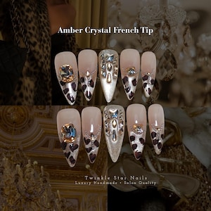 Puede incluir: Un juego de diez uñas postizas en forma de almendra con diseño Amber Crystal French Tip. Las uñas tienen una base nude con puntas de purpurina plateada, manchas de leopardo marrón oscuro y grandes cristales de color ámbar.