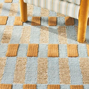 May include: A blue and brown checkered rug with a scalloped edge. The rug is made of a soft, textured material and has a subtle sheen.
