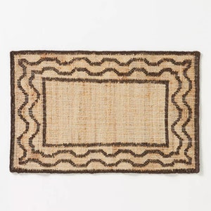 May include: A rectangular brown and beige jute rug with a wavy border design.