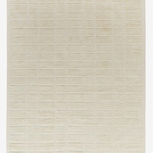 May include: A cream-coloured woven rug with a grid pattern. The rug is made of natural fibres and has a textured surface.