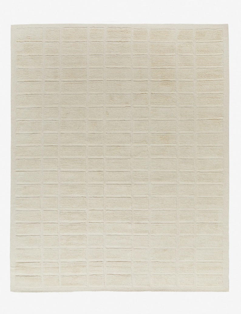 May include: A cream-coloured woven rug with a grid pattern. The rug is made of natural fibres and has a textured surface.