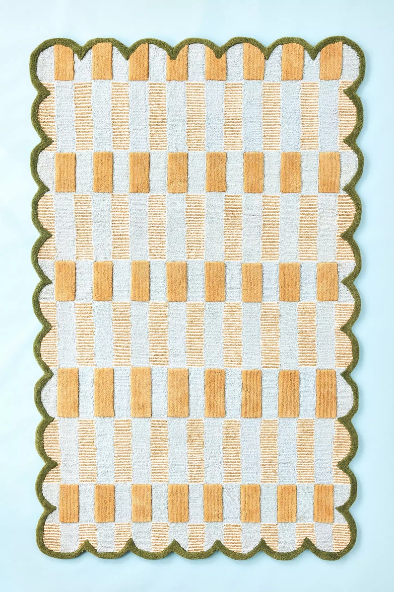 May include: A white and yellow checkered bath mat with a scalloped green border.