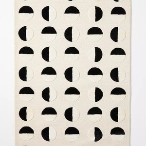 May include: A white rug with a repeating pattern of black and white half circles.
