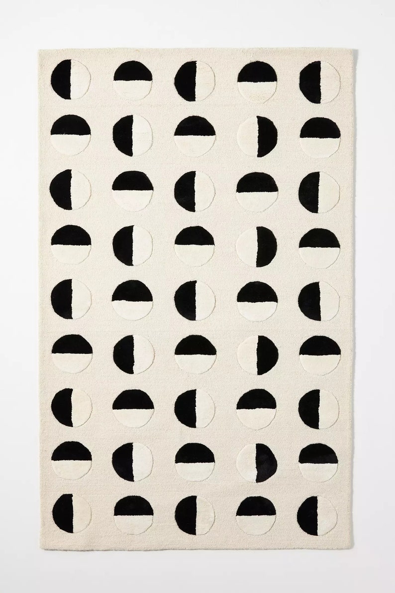 May include: A white rug with a repeating pattern of black and white half circles.