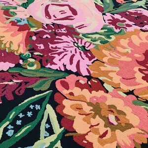 Puede incluir: Una alfombra negra con un patr&oacute;n floral con flores rosas, rojas y naranjas. Las flores son estilizadas y tienen una apariencia texturizada.