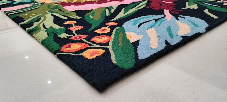 Puede incluir: Una alfombra negra con un estampado floral colorido. La alfombra presenta grandes flores azules, rosas y verdes con acentos amarillos y naranjas.