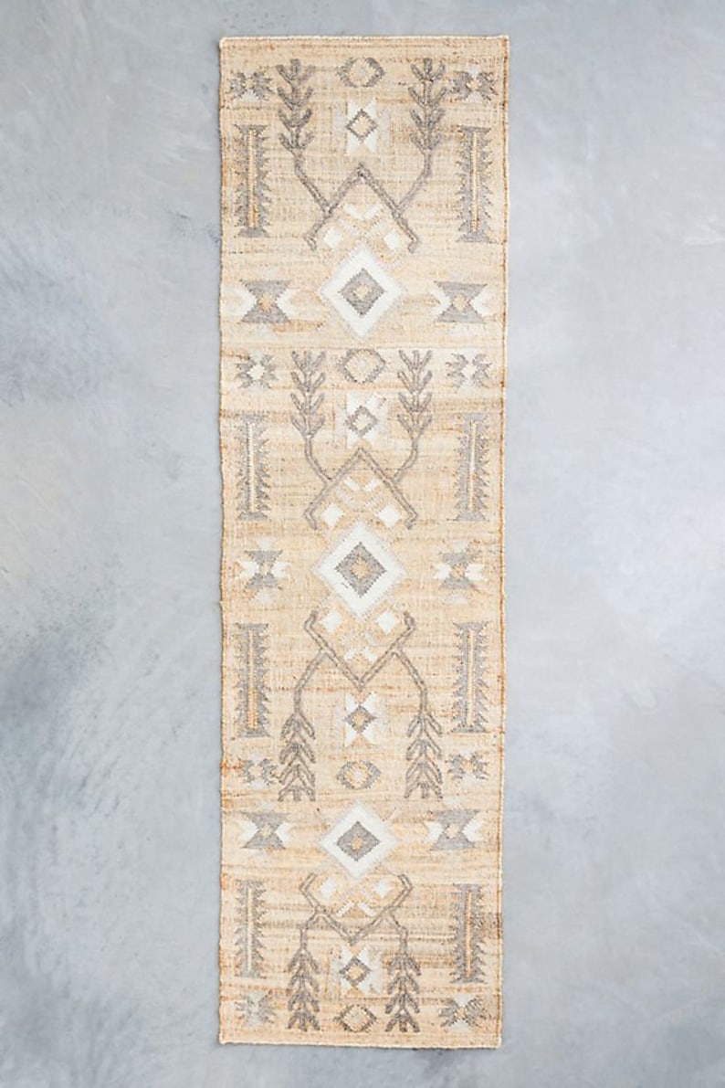 May include: A beige and gray patterned runner rug with a geometric design. The rug has a subtle sheen and a woven texture.