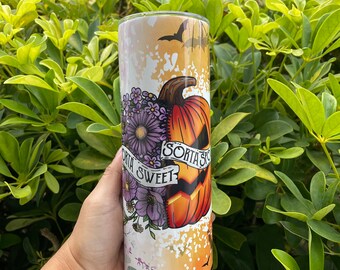 May include: A cylindrical tumbler featuring a split design with purple flowers on one side and an orange jack-o'-lantern on the other. A white banner across the center displays the text "SORTA SWEET" and "SORTA SPOOKY" with small black bats.