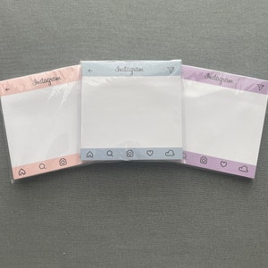 May include: Three Instagram-themed sticky note pads with different colored borders. The top border of each pad is light blue, light purple, and pink. Each pad has the word "Instagram" printed on the top border. The bottom border of each pad has a row of icons: a house, a magnifying glass, a camera, a heart, and a cloud.