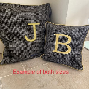 Puede incluir: Dos cojines decorativos, uno grande y otro peque&ntilde;o, ambos con un estampado de puntos azul marino y blanco. El coj&iacute;n m&aacute;s grande tiene una letra dorada "J", y el m&aacute;s peque&ntilde;o tiene una letra dorada "B". Ambos cojines tienen ribetes dorados.
